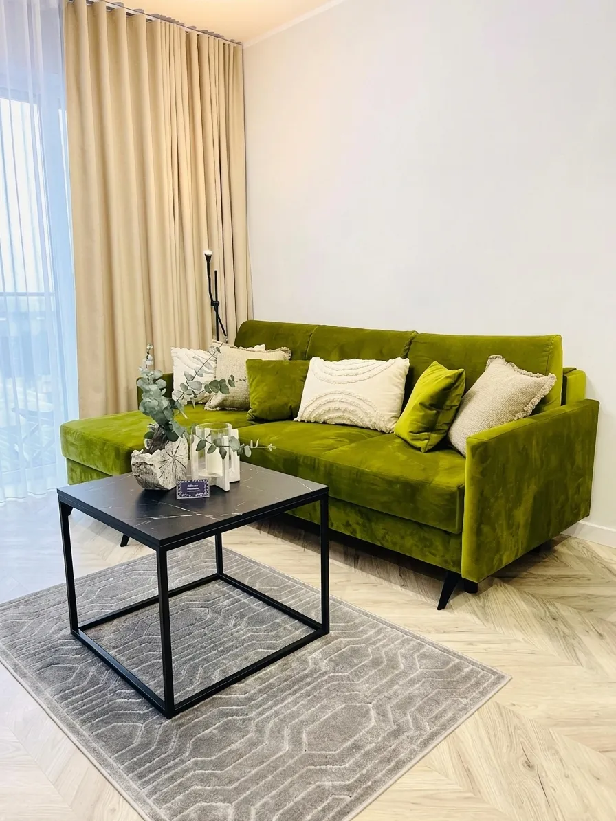 Zielona aksamitna sofa narożna w salonie